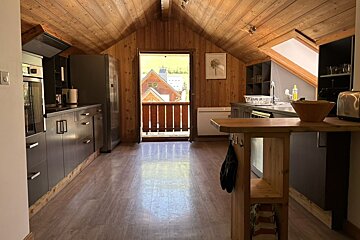 A kitchen with a wooden ceiling and a balcony