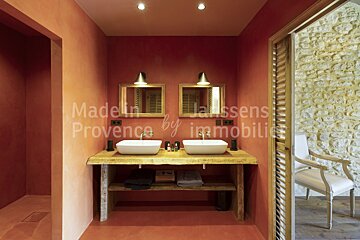 A bathroom with red walls and two sinks says madelin janssens provence by immobilier