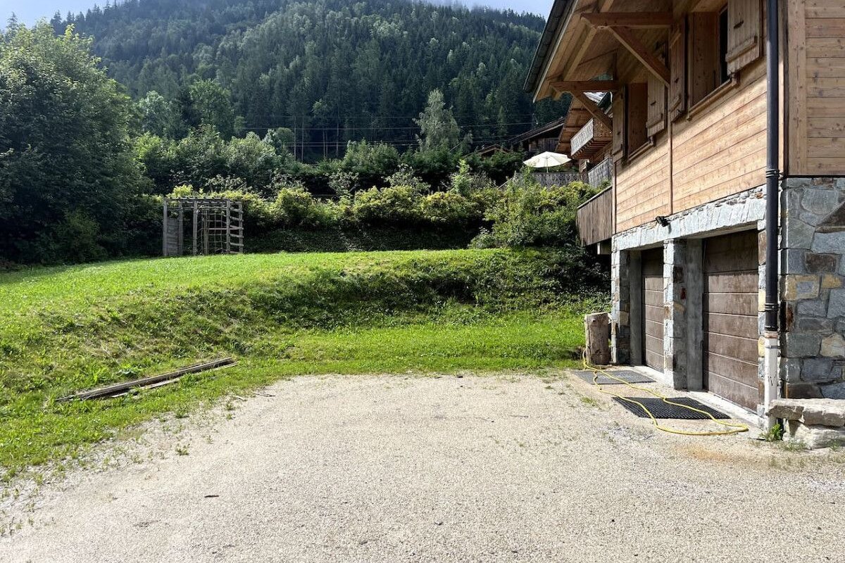 A wooden house with a garage and a mountain in the background