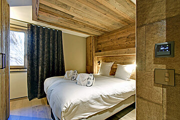 A bedroom with a bed and a thermostat that shows the time as 10:08