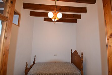 A bedroom with a bed and a chandelier hanging from the ceiling