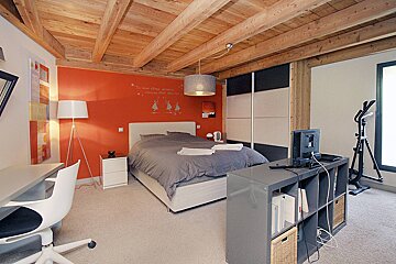 A bedroom with a bed a desk and a mirror