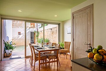 A dining room with a table and chairs and a bowl of fruit
