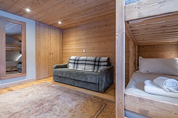A bedroom with bunk beds and a couch with a plaid blanket on it