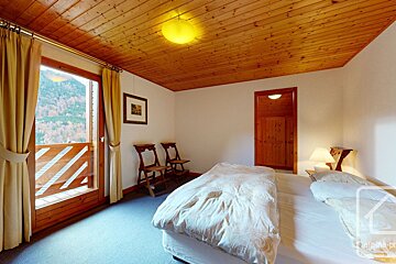 A bedroom with a wooden ceiling and a bed