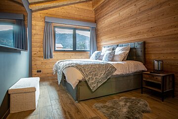 A bedroom with a bed and a window with mountains in the background