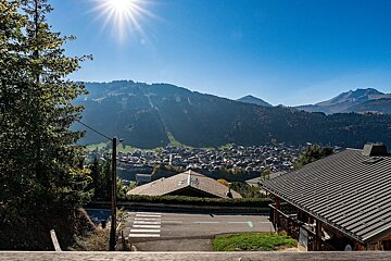 A scenic view of a mountain village nestled in a valley, captured from an elevated spot on a bright, sunny day.