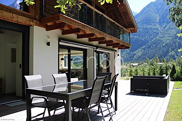 A table and chairs on a deck with mountains in the background