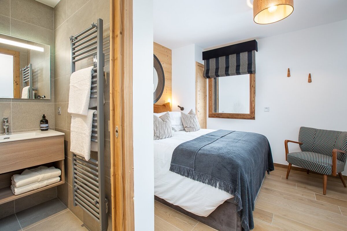 A bedroom with a large bed and a chair