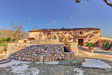 A stone wall in front of a house with a blue sky in the background