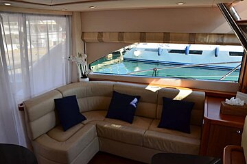 A couch with blue pillows sits in front of a window with a boat in the background