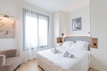 A bedroom with a picture of a sailboat on the wall above the bed