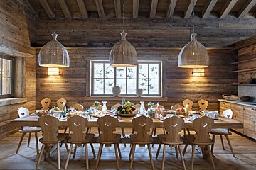 A wooden dining room with a long table and chairs