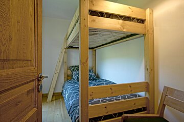 A bedroom with a bunk bed and a chair
