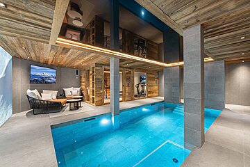 A large indoor swimming pool with a tv above it