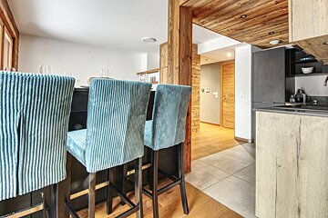 A kitchen with blue striped bar stools and wooden cabinets