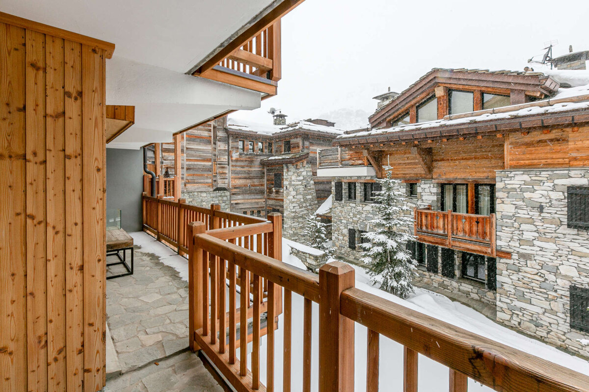 A wooden balcony with a stone building in the background