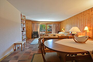 A living room with wood paneling and a table and chairs
