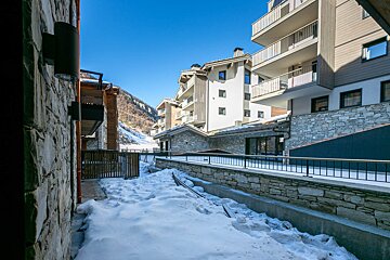 A snowy walkway between two buildings with mountains in the background