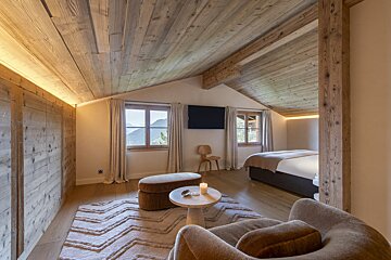 A bedroom with a wooden ceiling and a flat screen tv