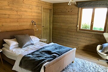 A bedroom with a bed a chair and a window