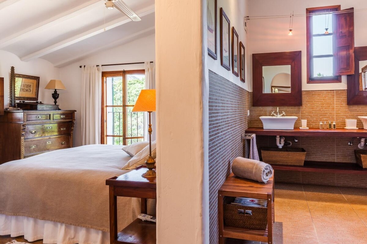 A bedroom with a large bed and a bathroom with a sink