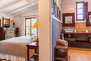 A bedroom with a large bed and a bathroom with a sink
