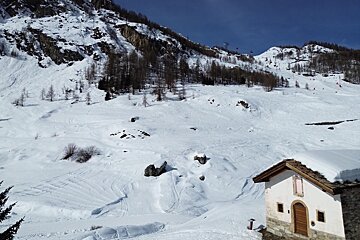 A snowy landscape with a small white building in the foreground