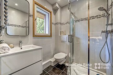A bathroom with a toilet a sink and a shower from mountain base
