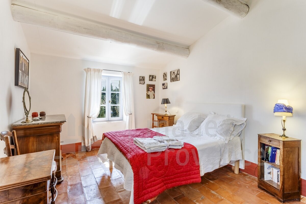 A bedroom with a bed that has a red blanket on it