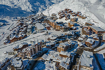 An aerial view of a snowy ski resort with mountains in the background