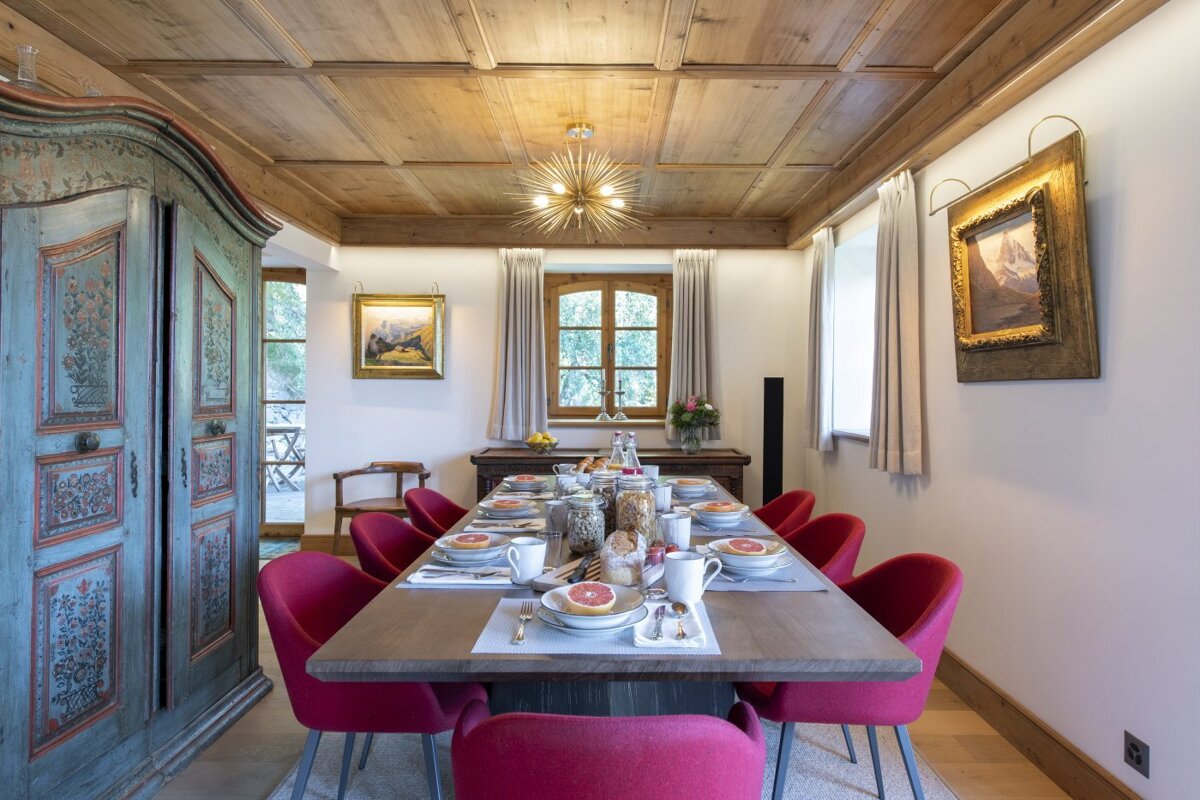 A dining room with a long table and red chairs