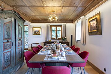 A dining room with a long table and red chairs