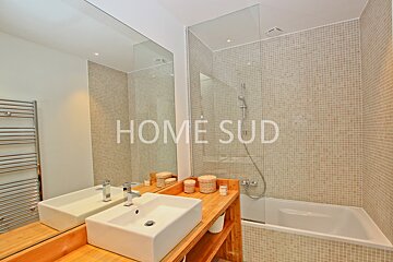 A bathroom with two sinks and a bathtub has home sud written on the wall