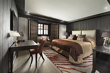 A bedroom with a large bed and a desk