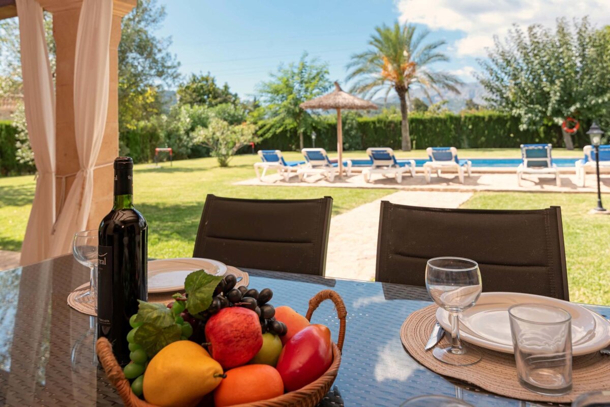 A basket of fruit sits on a table next to a bottle of wine