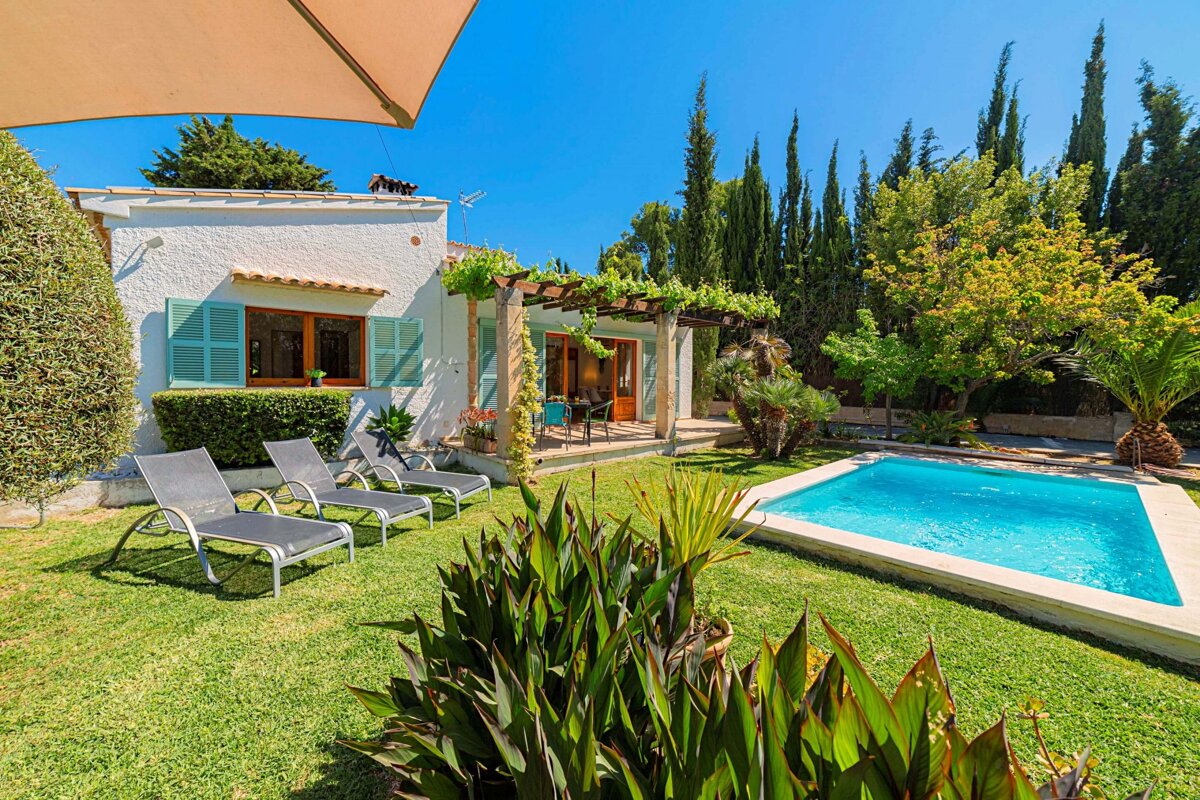 A white house with a swimming pool in front of it