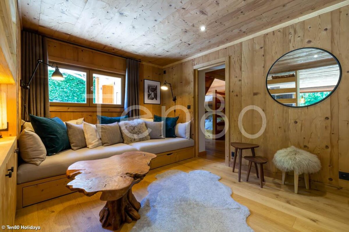A living room with a wooden couch and a round mirror