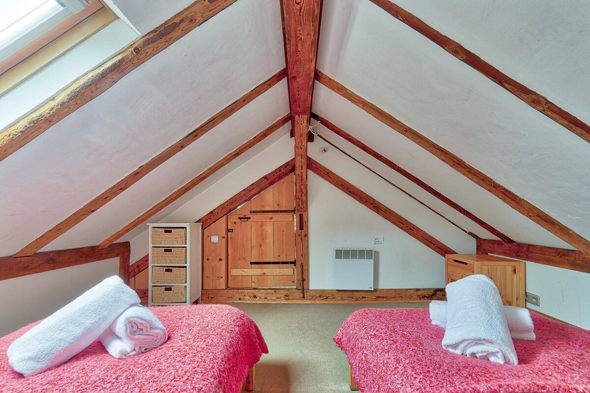 A bedroom with two beds and a shelf with baskets on it