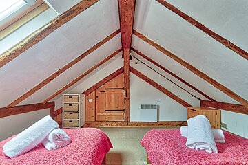 A bedroom with two beds and a shelf with baskets on it