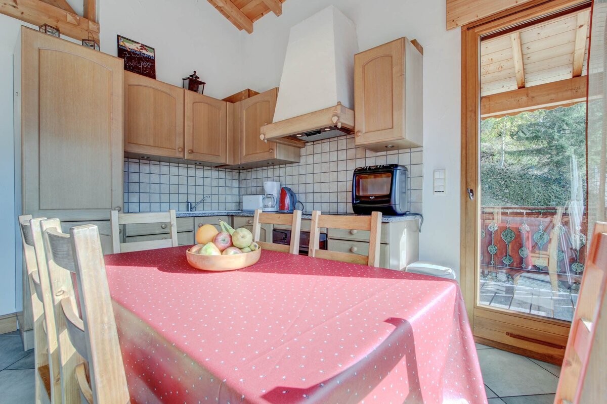 A bowl of fruit sits on a table in a kitchen
