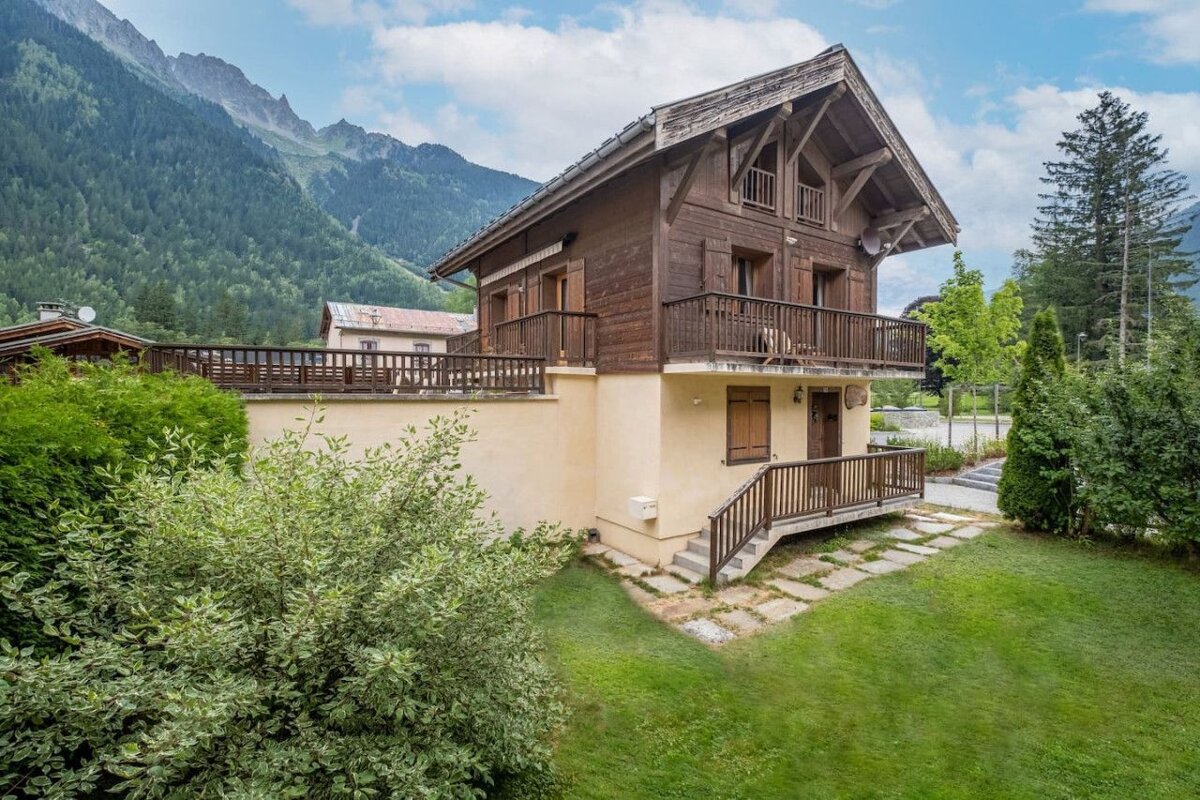A house with a balcony and mountains in the background