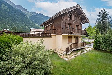 A house with a balcony and mountains in the background