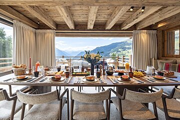 A dining room table with a view of the mountains in the background