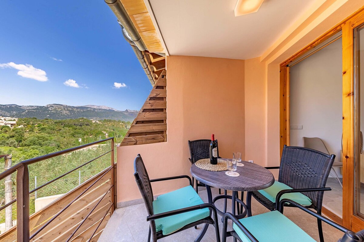 A balcony with two chairs and a table with a bottle of wine on it