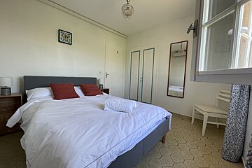 A bedroom with a bed a chair and a mirror