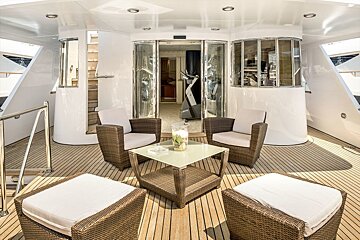A deck with wicker furniture and a glass table