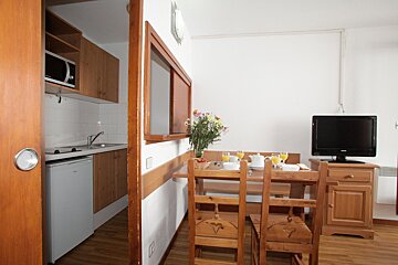 A dining room with a table and chairs and a flat screen tv
