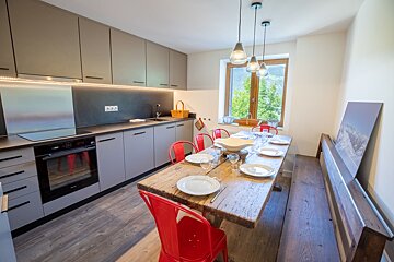A kitchen with a wooden table and red chairs