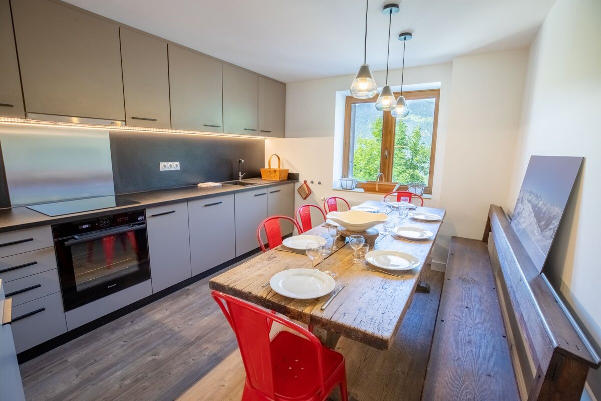 A kitchen with a wooden table and red chairs